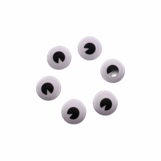 An image of six 1 inch white, edible candy eyeballs with black pupils of varying sizes. These whimsical decorations can transform any confection into a character with their engaging gaze, perfect for themed parties or playful dessert presentations.