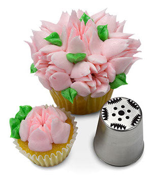A cupcake and mini cupcake decorated with pink buttercream petals and green leaves, alongside a specialized Russian piping tip with a serrated edge, designed for creating realistic flower designs.