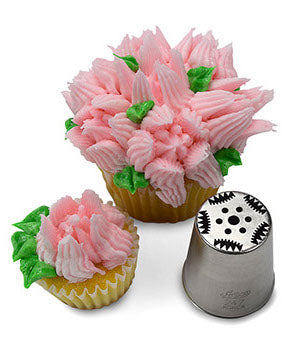 Cupcake decorated with intricate white and pink frosting flowers and green leaves, made using Russian Piping Tip #247. The corresponding metal piping tip is shown beside the cupcake, highlighting its precise pattern.