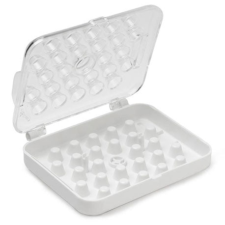Open piping tip storage box showing molded white base with 26 slots for small piping tips, coupler, and flower nails, and a hinged clear lid