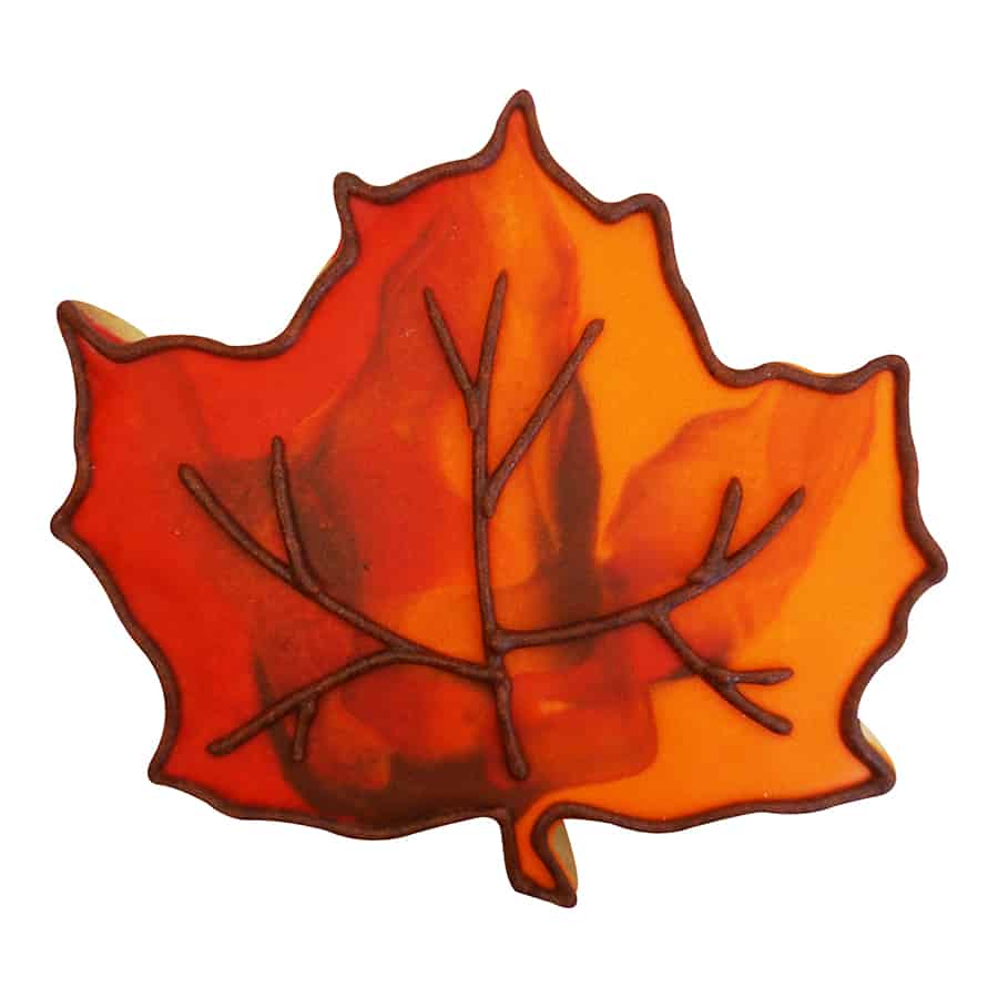 Decorated orange and red maple leaf cookie with marbled icing, showcasing fall-inspired design.