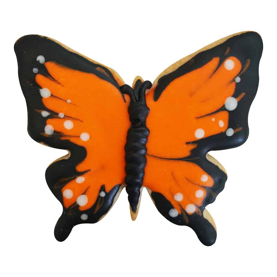 Decorated butterfly cookie with vibrant orange and black icing, designed as a monarch butterfly.