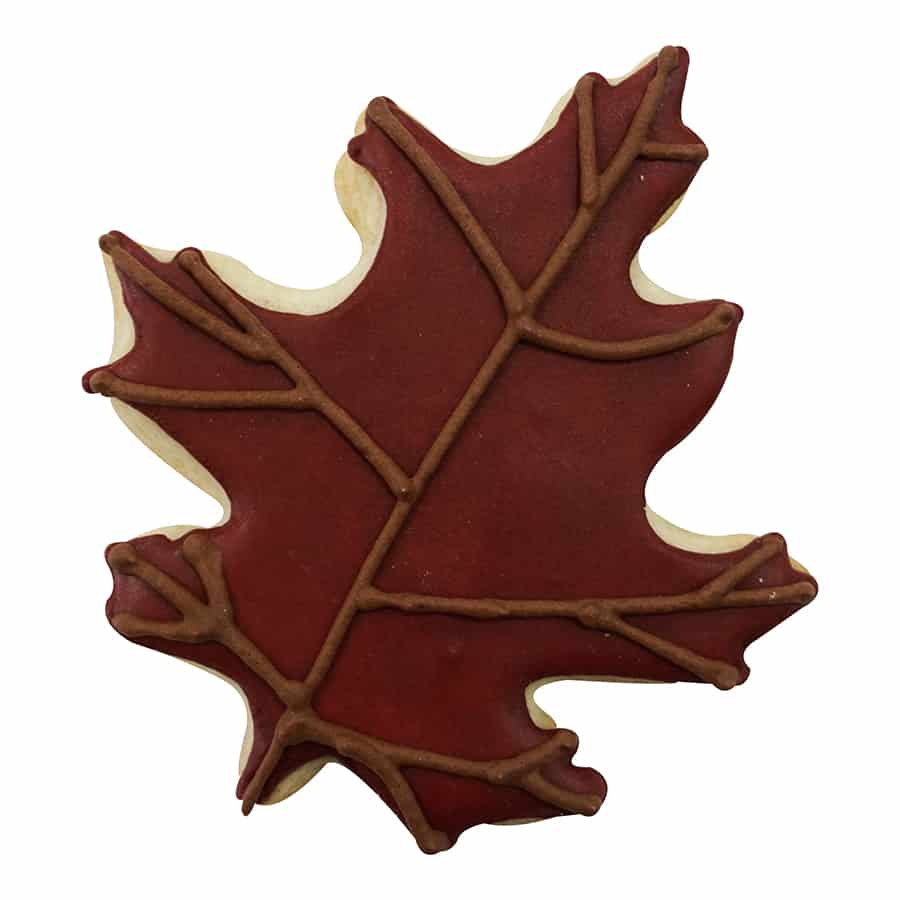 Decorated oak leaf cookie with a deep red base and brown vein detailing for a fall-inspired look.