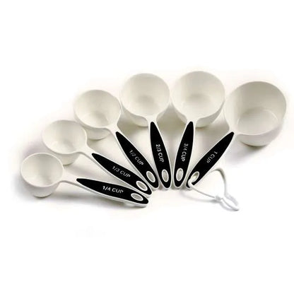 Set of white measuring cups with black handles, including 1/4 cup to 1 cup measurements, with some cups filled with brown sugar and displayed on a white surface.