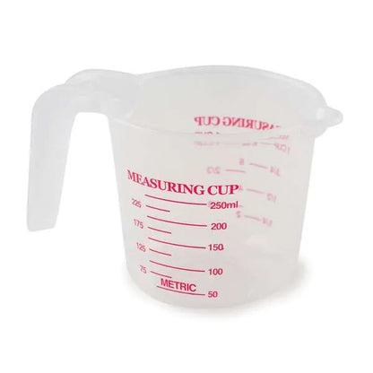 Small transparent plastic measuring cup with red markings showing measurements in milliliters and cups, specifically labeled up to 250 milliliters or 1 cup.