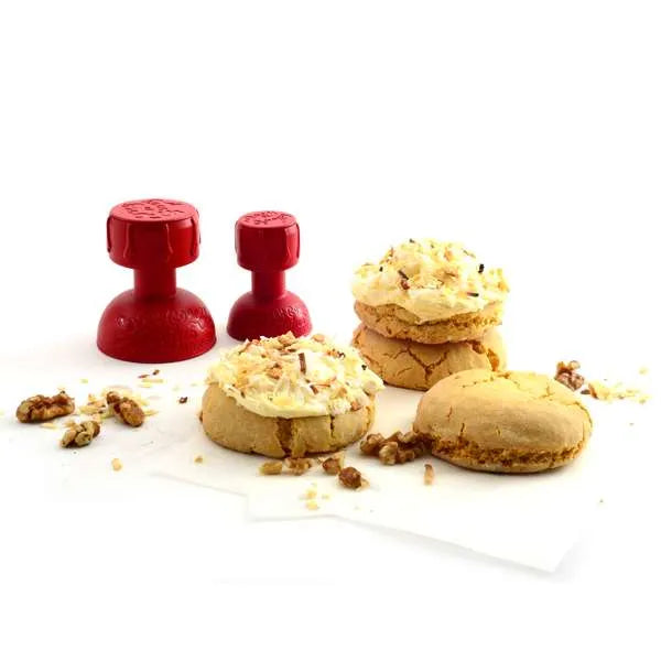 Red tampers and walnut-topped cookies on parchment paper.