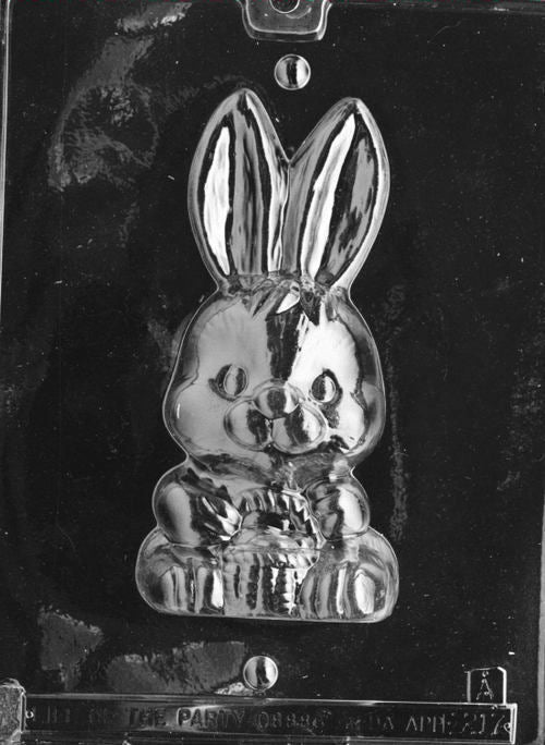 Clear plastic chocolate mold showing the front half of a bunny with long upright ears holding a basket in its paws, with facial details and textured basket lines.