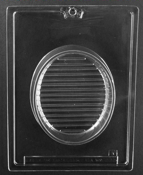 Clear plastic chocolate mold showing an oval pour box base cavity with horizontal line texture, designed to pair with a decorative lid to form a filled chocolate box.