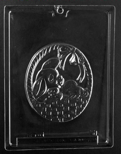 Clear plastic chocolate mold showing a flat oval design of a bunny sitting in a woven basket with ribbon detail, intended as the top piece for a pour box-style chocolate.