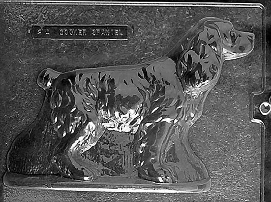Clear plastic chocolate mold showing the front half of a seated Cocker Spaniel with long curled ears, textured coat detail, and a rounded base edge.