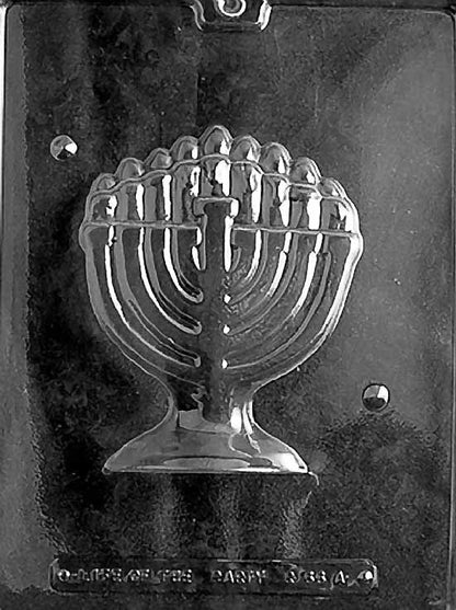 Clear plastic chocolate mold showing one half of a detailed menorah with curved arms, candle shapes across the top, and a pedestal base for a 3D Hanukkah chocolate.