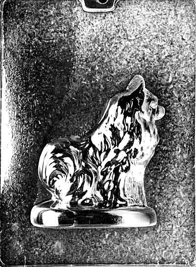 Clear plastic chocolate mold showing the front half of a seated Pomeranian with a thick textured coat, perky ears, and a curled fanned tail on a rounded base.