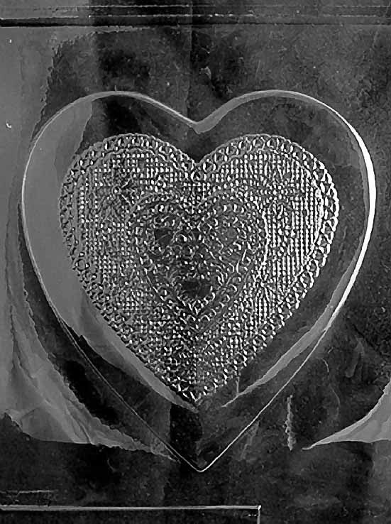 Clear plastic mold featuring a large heart-shaped chocolate lid with layered, textured heart designs and ornate scroll-style embossing.