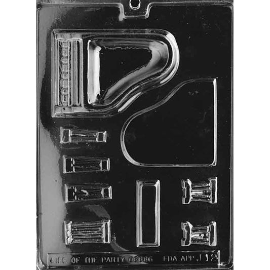 Clear plastic chocolate mold with multiple cavities for assembling a 3D grand piano, including the piano body, curved lid, keyboard detail, and smaller accessory pieces.