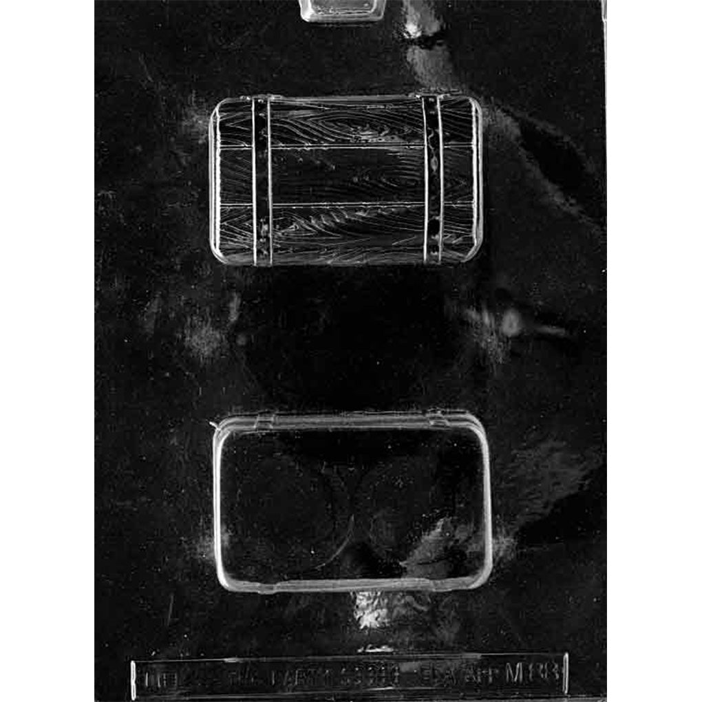 Clear plastic treasure chest chocolate mold with two rectangular chest cavities, one showing wood grain and strap details and one smooth backing cavity, on a dark background.