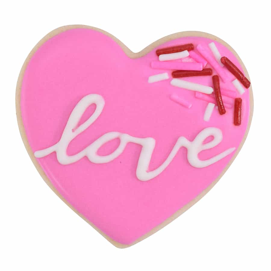 Heart-shaped cookie decorated with pink icing, white lettering that says 'love,' and colorful sprinkles.