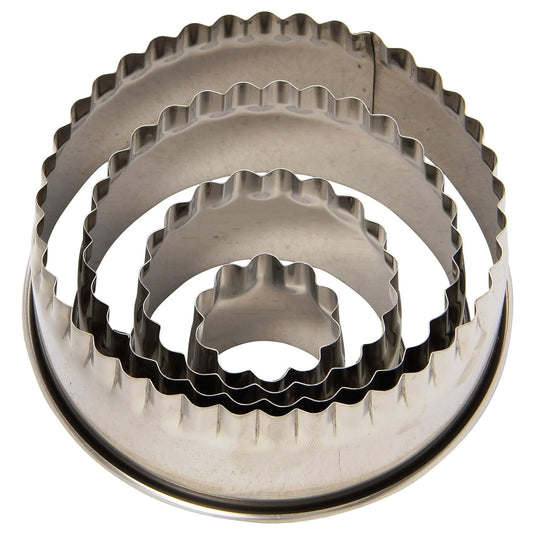 Nested set of four stainless steel round fluted cookie cutters stacked inside each other, showing scalloped edges in multiple sizes on a white background.