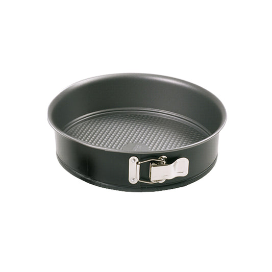 Empty round 7-inch black nonstick springform pan with a textured base and shiny silver latch, photographed against a white background.