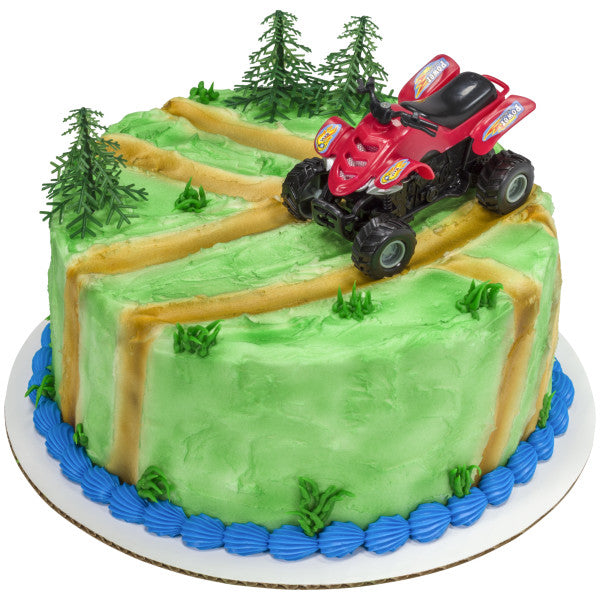 Round cake with a rugged outdoor design, complete with ATV topper and tree picks on a green landscape with dirt trails.