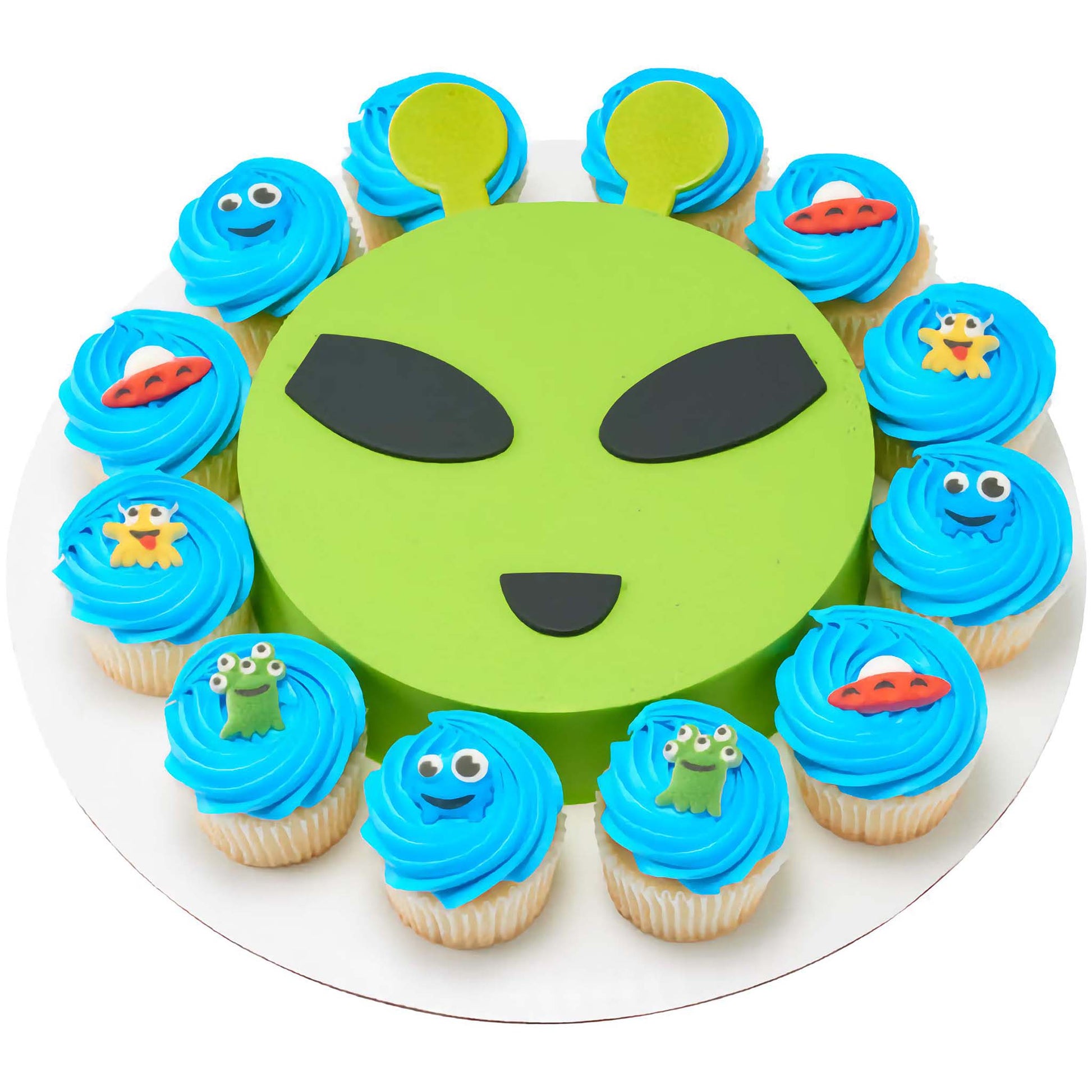 Vibrant alien-themed party dessert set with blue frosted cupcakes and a large green cake shaped like an alien's face, decorated with pressed sugar alien figures and yellow ear-like toppers.