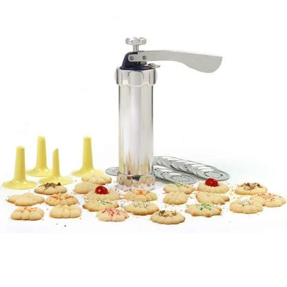 Cookie press surrounded by freshly made spritz cookies with cherries and sprinkles.