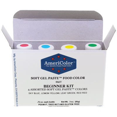 AmeriColor Soft Gel Paste Beginner Kit box open to reveal four gel food coloring bottles in red, blue, yellow, and green with labeled caps.
