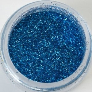 Small jar of blue galaxy glitter spilling onto a white surface. Non-edible