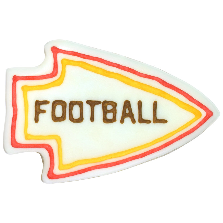 Decorated arrowhead-shaped cookie with white icing base, red and yellow piped border lines, and brown lettering across the center on a white background.