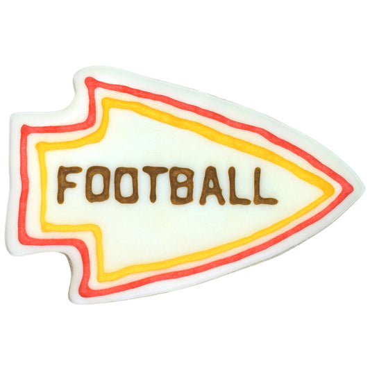 Decorated arrowhead-shaped cookie with white icing base, red and yellow piped border lines, and brown lettering across the center on a white background.