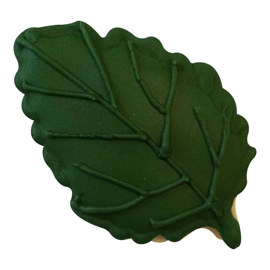 A finished cookie shaped like an aspen leaf, decorated in a vibrant green with detailed vein imprints.