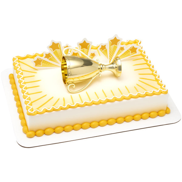 A rectangular cake with gold and white decorations, featuring the trophy topper and starburst accents.