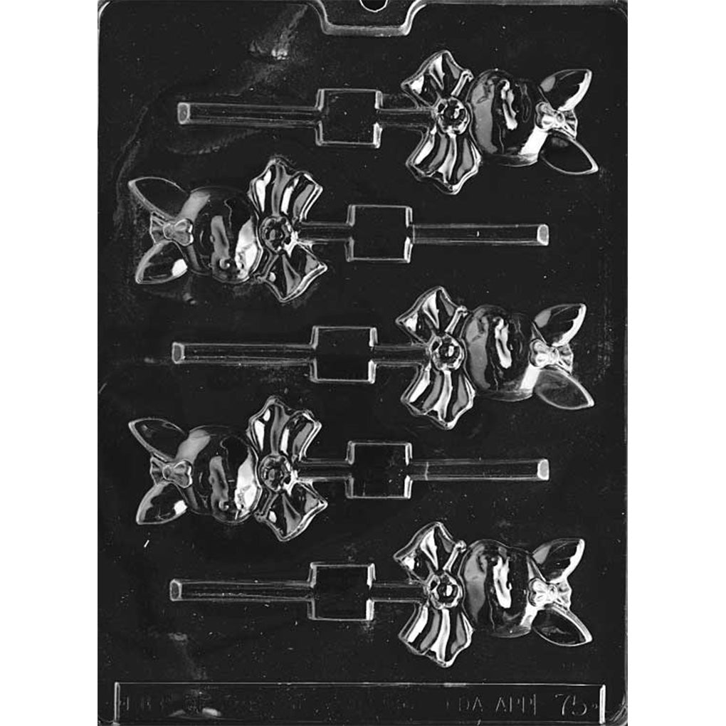 Bunny girl face chocolate lollipop mold with six cavities on a dark plastic tray, each showing a bunny face with upright ears, a small hair bow, and a large ribbon bow at the neck with stick channels.