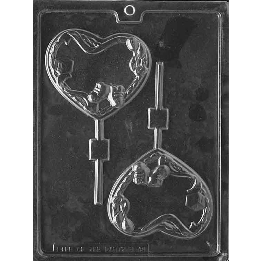 Clear plastic chocolate lollipop mold with two heart-shaped cavities, each decorated with raised baby-themed details including baby booties, blocks, and a rattle, shown on a dark background.