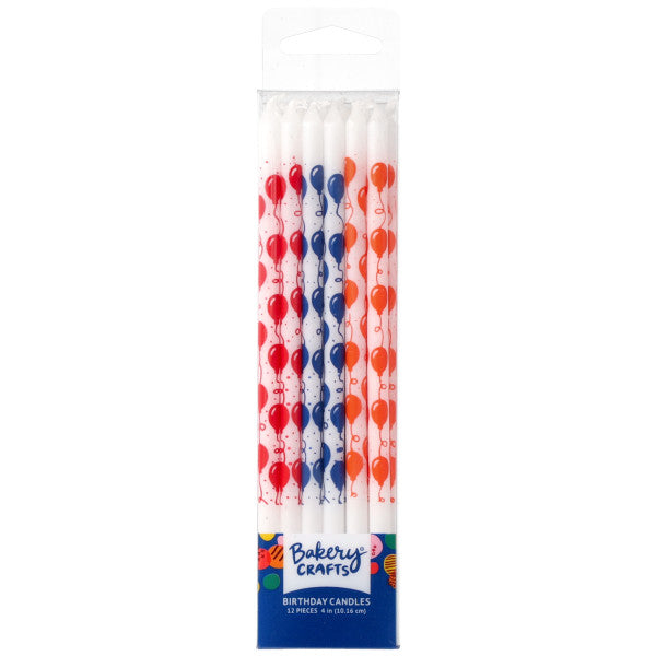 Pack of white birthday candles in a clear plastic box, each candle printed with red, blue, and orange balloons and confetti dots, with a Bakery Crafts label at the bottom.