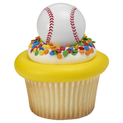 Cupcake with white frosting, rainbow sprinkles, and a baseball ring topper.