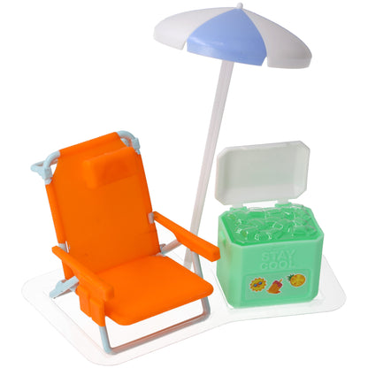 Close-up of a beach-themed cake topper set with an orange lounge chair, blue-and-white umbrella, and green cooler on a clear display tray.