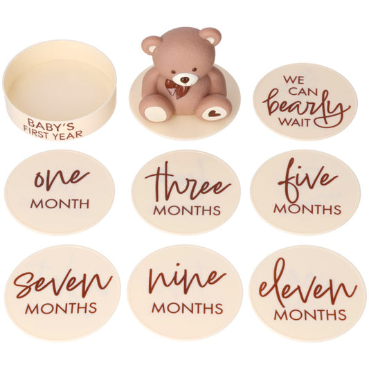 Beary First Year cake kit pieces on a white background, featuring a brown teddy bear topper and cream round date disks with month text and “We can bearly wait” lettering.