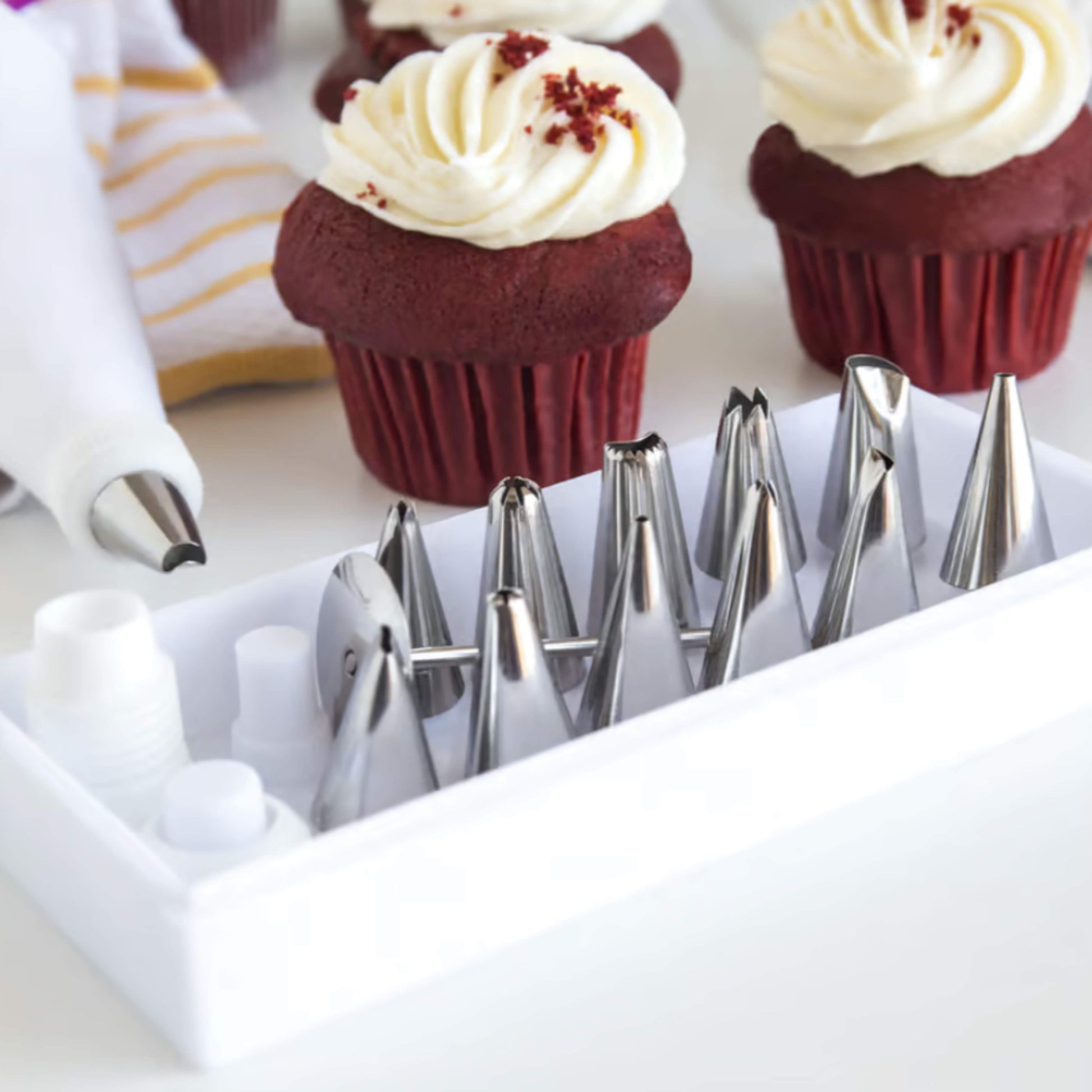 17 Piece Piping Tip set in a holder with red velvet cupcakes in the background