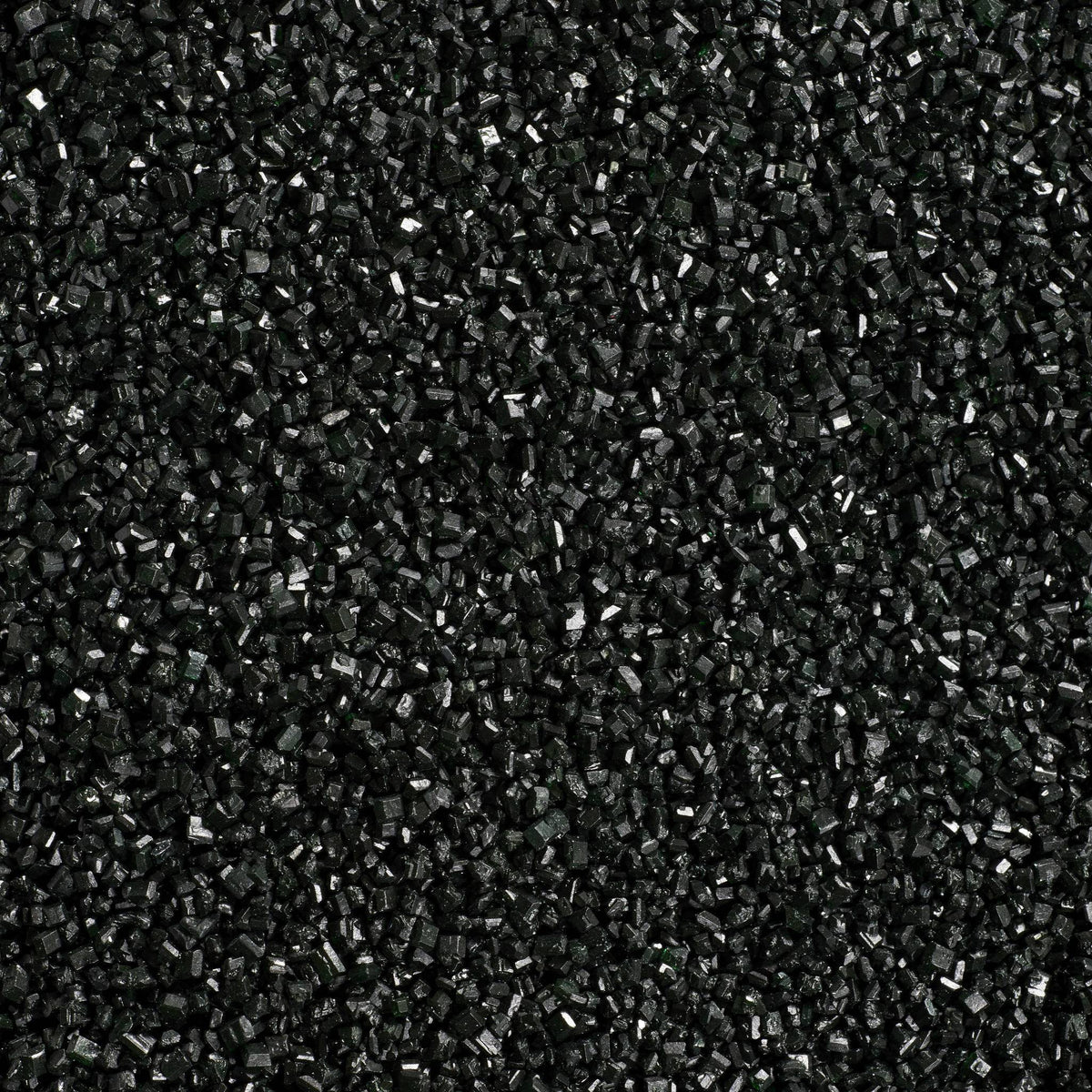 Close-up texture of black sanding sugar showing densely packed, coarse black sugar crystals with small reflective surfaces and a subtle sparkle.