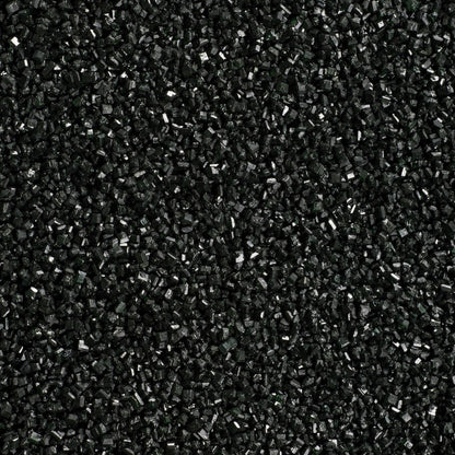 Close-up texture of black sanding sugar showing densely packed, coarse black sugar crystals with small reflective surfaces and a subtle sparkle.