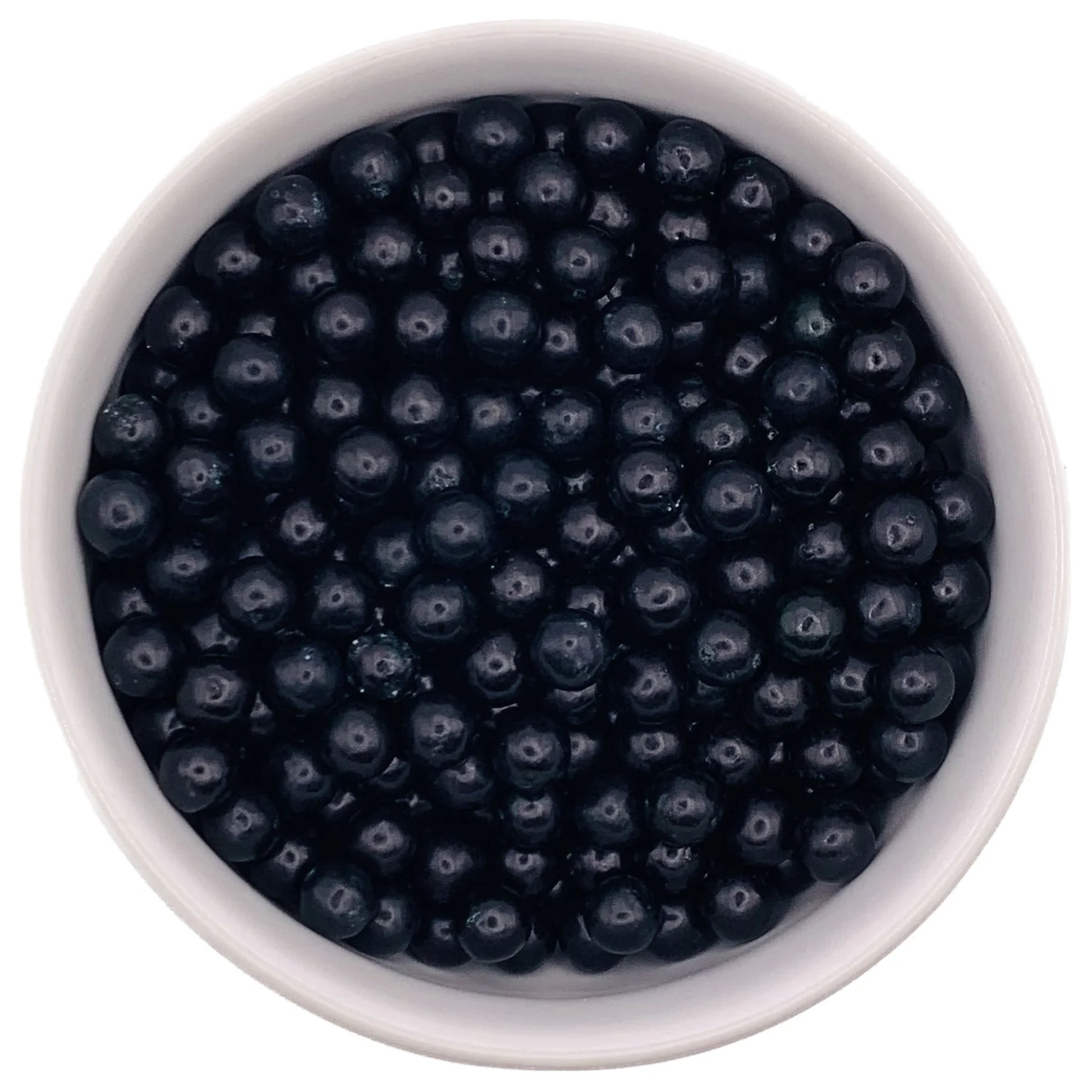 Top-down view of a white bowl filled with 7mm glossy black sugar pearls, used for decorating cakes and desserts.