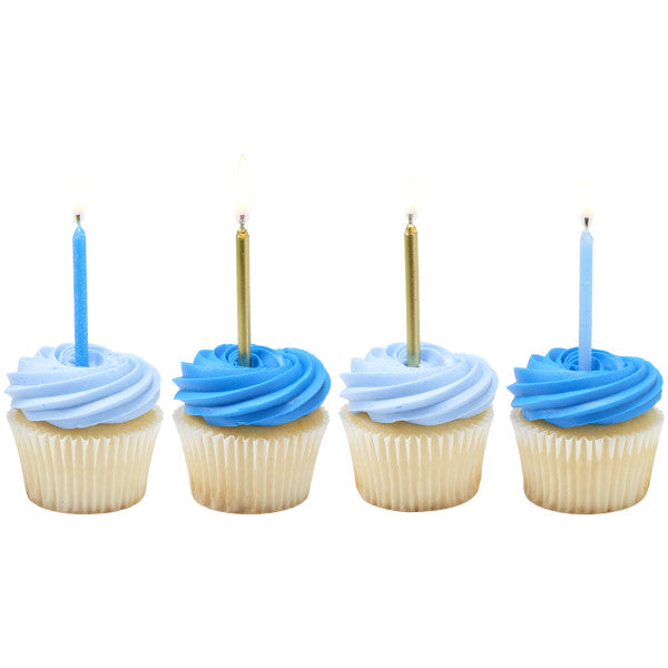 Four cupcakes topped with light blue and dark blue buttercream swirls, each finished with a tall birthday candle in light blue or metallic gold.