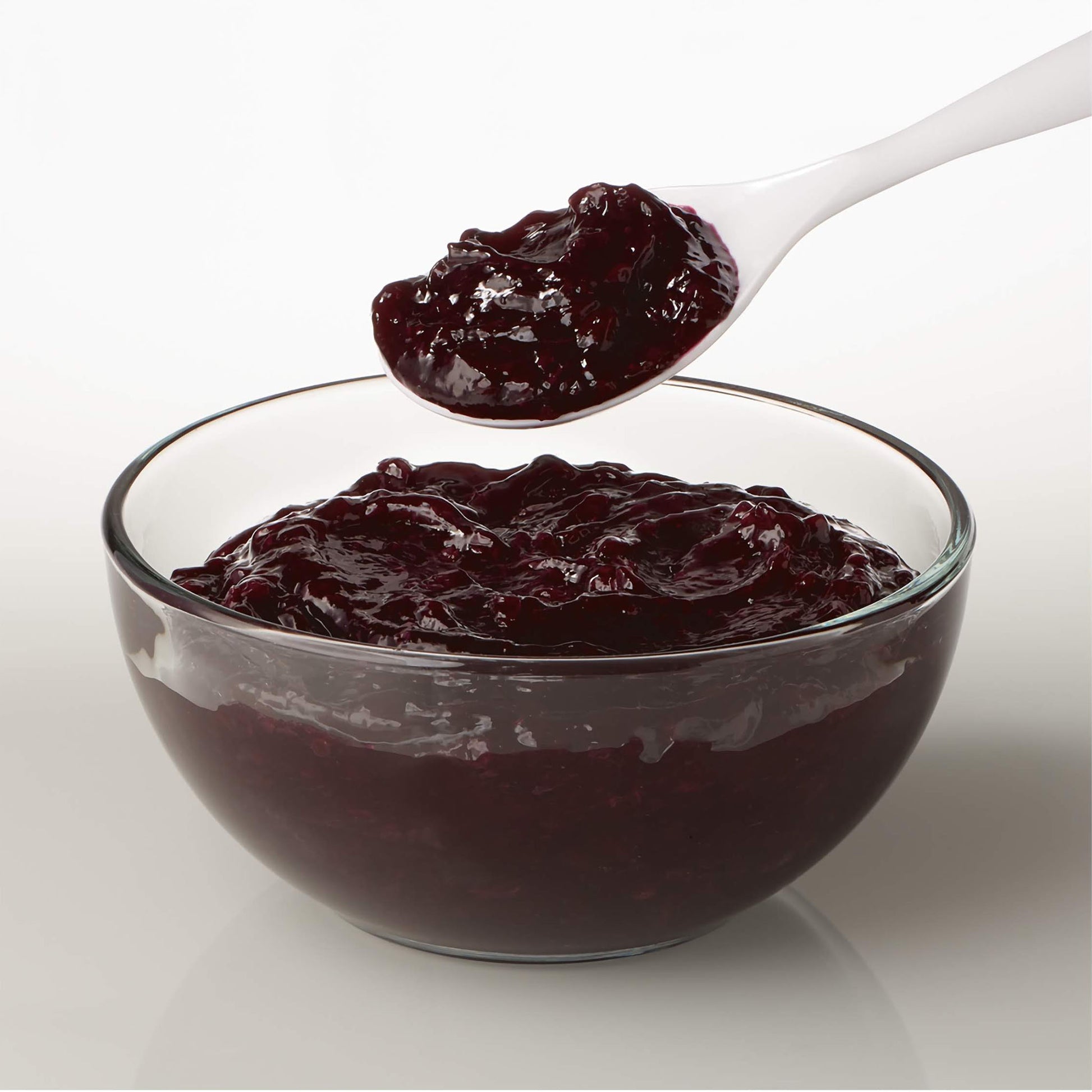 Spoonful of thick blueberry pastry filling being lifted from a glass bowl, showing rich, glossy texture.
