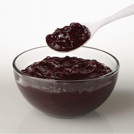 Spoonful of thick blueberry pastry filling being lifted from a glass bowl, showing rich, glossy texture.