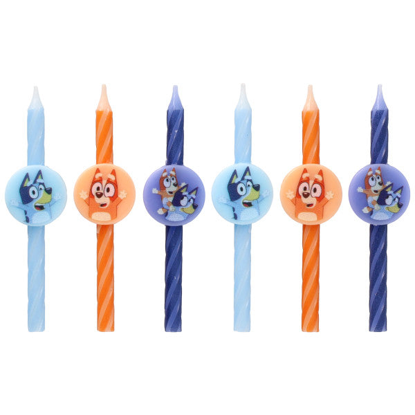 Six Bluey birthday candles in light blue, orange, and dark blue with swirl stripes and round character medallions, displayed in a row on a white background.