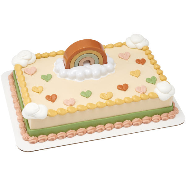 A rectangular cake with soft pastel decorations, featuring the boho rainbow topper and cloud embellishments.