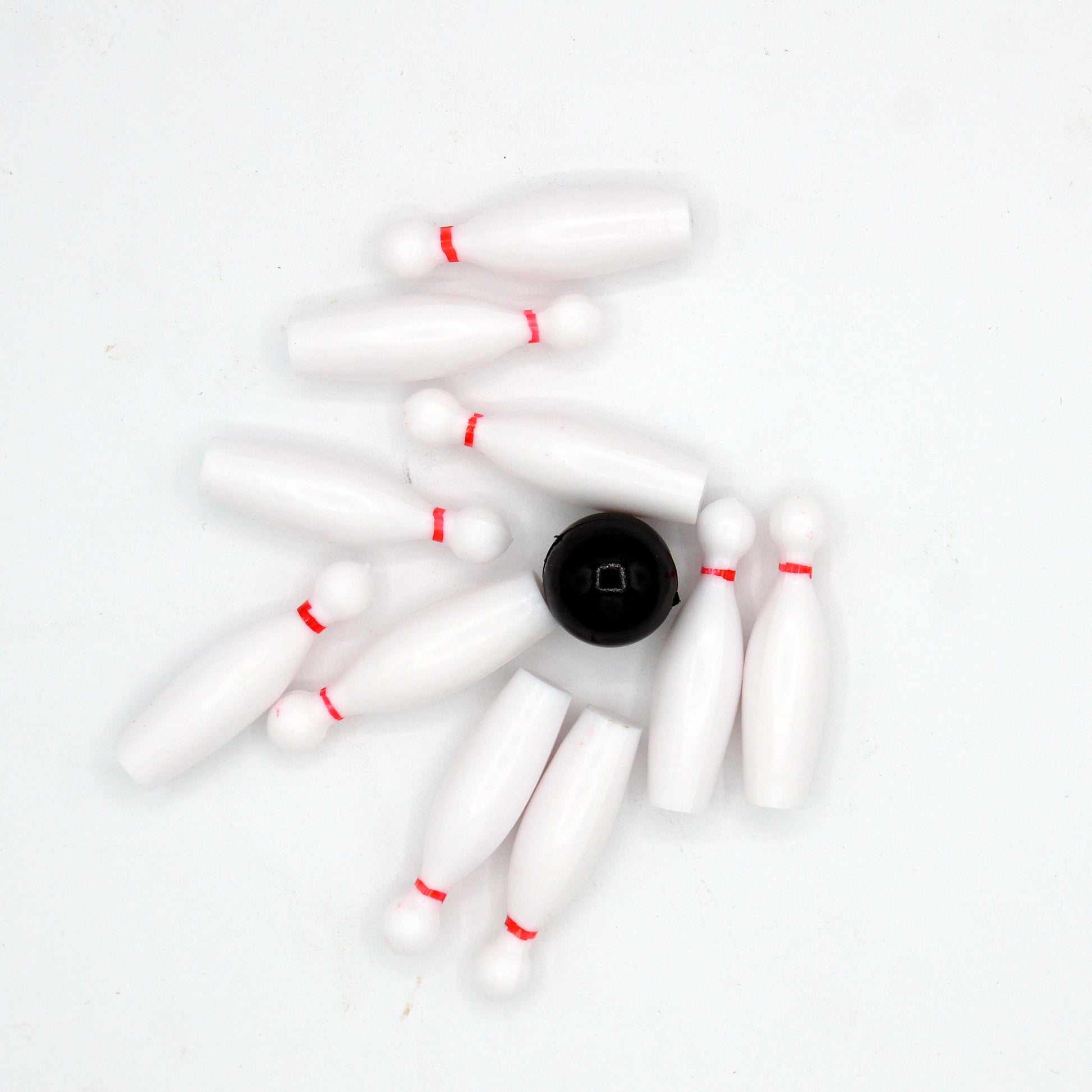Bowling cake toppers scattered with the black ball in the center after a strike.