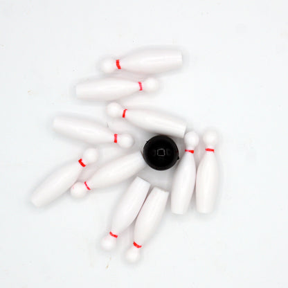 Bowling cake toppers scattered with the black ball in the center after a strike.