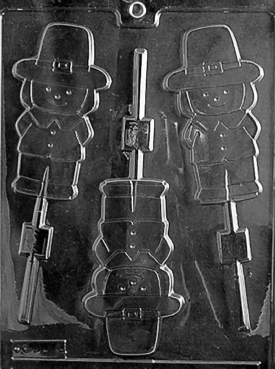 Clear chocolate lollipop mold with three cavities shaped like a boy pilgrim wearing a hat and collar, each aligned with stick channels on a glossy plastic sheet.