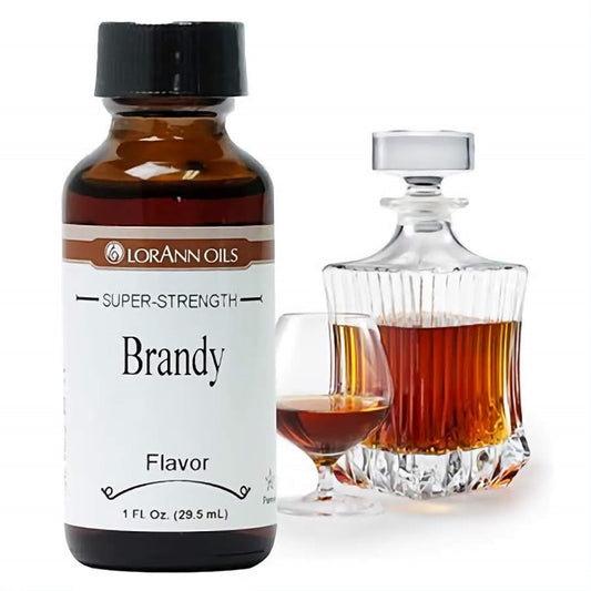A 1 fl oz bottle of LorAnn Oils Super Strength Brandy Flavor, placed next to a crystal decanter and snifter filled with amber-colored brandy, mirroring the sophisticated flavor.